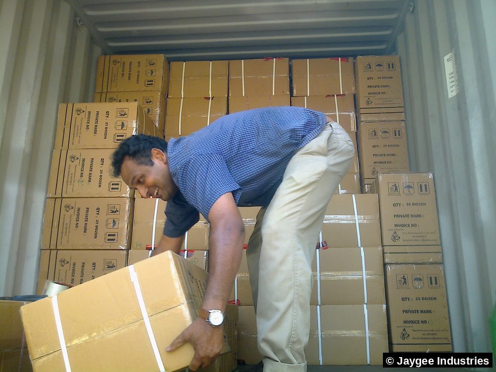 Jaygee Industries team member smiling while loading export cartons into a shipping container