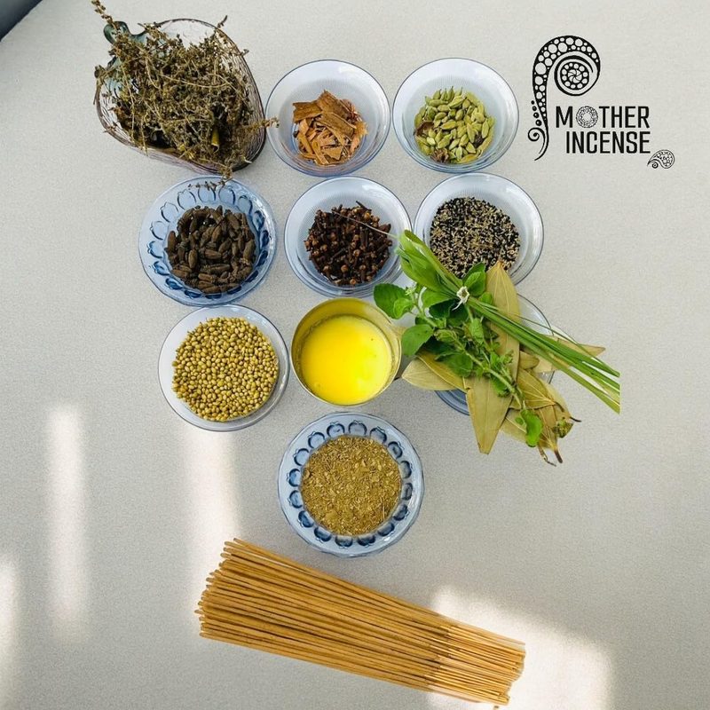 Mother Incense ingredients flat-lay — herbs in glass vase, spice bowls: cinnamon, cardamom, cloves, ghee and bamboo sticks